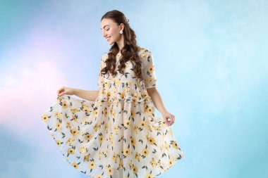 Açık mavi arka planda, dumanlı, güzel giyimli genç bir kadın.