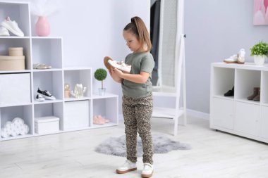 Küçük kız dükkanda farklı ayakkabılar deniyor.