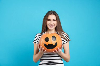 Mutlu Cadılar Bayramı. Açık mavi arka planda balkabağı kabağı olan kadın.