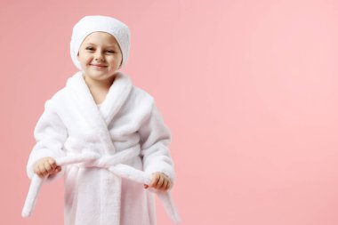 Pembe arka planda sarılı saçı olan bornozlu tatlı bir kız. Metin için boşluk