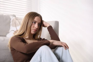 Evdeki kanepenin yanındaki depresyondaki genç kız.