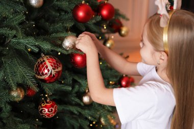 Evde Noel ağacı süsleyen küçük kız.
