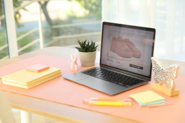 Ofisteki ahşap masada dizüstü bilgisayarı, dekoru ve pembe paspası olan şık bir iş yeri.