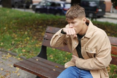 Genç adam mide ağrısı ve açık havada mide bulantısı çekiyor. Metin için boşluk