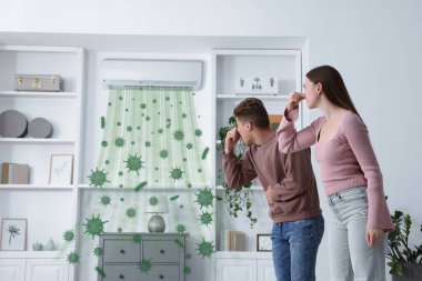 İçerideki klimanın kötü kokusu yüzünden burunlarını kapatan bir çift. Kirli hava, cihazdan gelen bakterilerle birlikte akıyor.