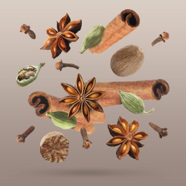 Noel içecekleri için farklı baharatlar ve kahverengi arkaplana düşen yemekler. Anason, kakule, tarçın, hindistan cevizi ve karanfil.