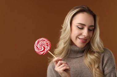 Noel kutlaması. Kahverengi arkaplanda lolipopu olan kadın, metin için boşluk
