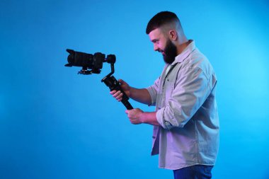 Açık mavi arkaplanda kameralı titreşim dengeleyici kullanan kameraman