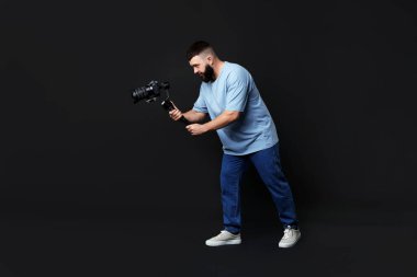 Kameraman siyah arkaplanlı, titreşimli dengeleyici kullanıyor. Metin için boşluk