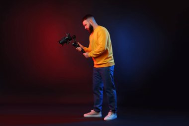 Kamerada çekim yapan kameraman, koyu arkaplandaki renk ışıklarına karşı titreşim dengeleyici kullanıyor.