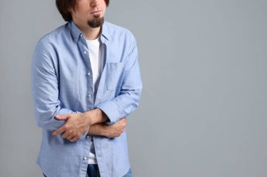 Gri arka planda mide ağrısı ve bulantı çeken bir adam, yakın plan. Metin için boşluk