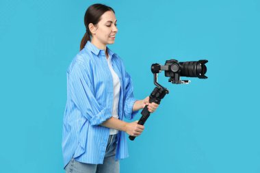 Açık mavi arkaplanda kameralı titreşim dengeleyici kullanan kameraman