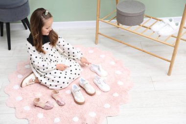 Küçük kız dükkanda farklı ayakkabılar seçiyor.