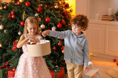 Evde Noel ağacının yanında süsleri olan sevimli çocuklar.