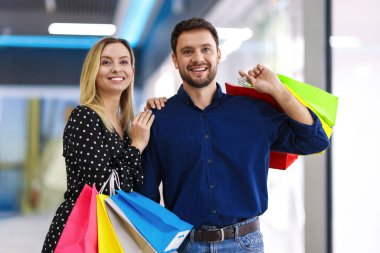 Alışveriş merkezlerinde farklı çantaları olan mutlu bir çift.