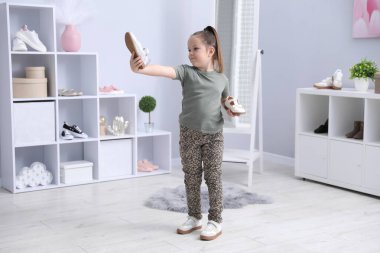 Küçük kız dükkanda farklı ayakkabılar deniyor.