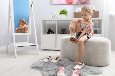 Küçük kız dükkanda farklı ayakkabılar deniyor.