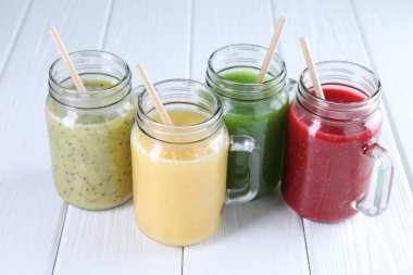 Beyaz ahşap masada, mason kavanozlarda farklı lezzetli içecekler.