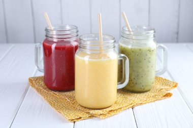 Beyaz ahşap masada, mason kavanozlarda farklı lezzetli içecekler.