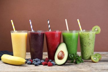 Farklı lezzetli içecekler, bardaklar ve malzemeler ahşap masada, yakın plan.