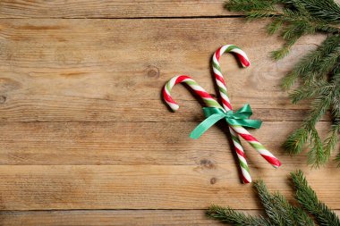 Ağaç dalları ve yaylı şeker kamışları ahşap masanın üzerinde, düzlük ve metin için yer var. Noel hediyesi