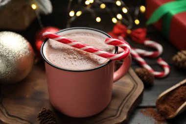 Lezzetli sıcak kakao içeceği, bardakta şeker kamışı ve ahşap masada Noel dekoru, yakın plan.