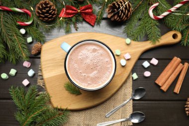 Bardakta sıcak kakao, marşmelov ve koyu ahşap masada Noel süsü.