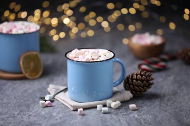 Gri masasında lokum bulunan lezzetli kakao bulanık Noel ışıklarına karşı, yakın plan.