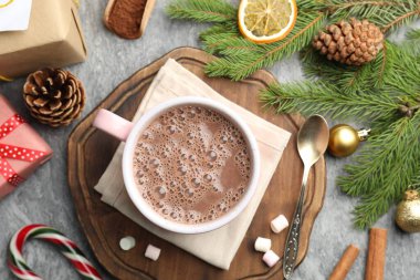 Lezzetli kakao, marşmelov, tarçın, şeker kamışı ve Noel süsü gri masada, düz uzanmış