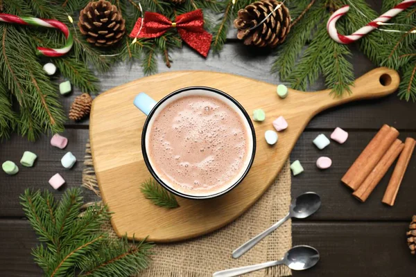 Bardakta sıcak kakao, marşmelov ve koyu ahşap masada Noel süsü.