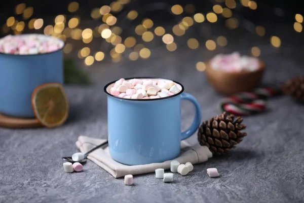 Gri masasında lokum bulunan lezzetli kakao bulanık Noel ışıklarına karşı, yakın plan.