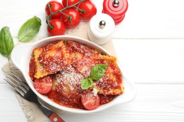 Beyaz ahşap masada servis edilen, domates soslu, peynirli ve fesleğenli ravioli. Metin için boşluk