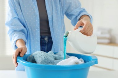 Kadın plastik havlulara deterjan döküyor. Kapalı bir masada havlular, yakın plan.