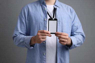 Gri arkaplanda boş rozet gösteren adam, yakın plan.