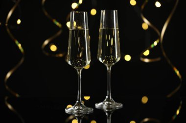 Yeni yıl kutlaması. Flüt bardaklarında köpüklü şarap ve siyah arka planda yılan şeklinde flamalar, bokeh ışıkları.