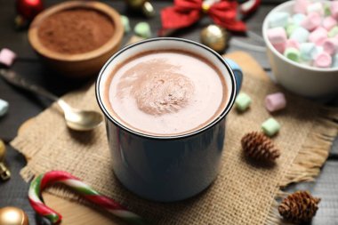 Bardakta sıcak kakao, marşmelov ve karanlık ahşap masada Noel süsü, yakın plan.