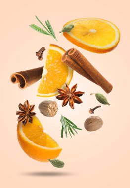 Pembe arka plana düşen sıcak şarap için portakal dilimleri ve baharatlar. Geleneksel Noel içkisi