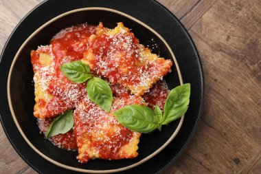 Ahşap masada domates soslu, peynirli ve fesleğenli lezzetli ravioli.