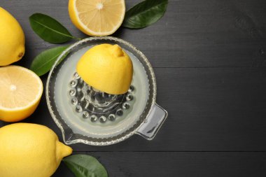 Taze limon suyuyla meyve sıkacağı, siyah ahşap masa üzerinde meyve ve yapraklar, düz yatak. Metin için boşluk