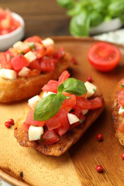 Domatesli lezzetli bruschettalar, mozzarella peyniri ve fesleğen masada servis edilir, yakın plan.