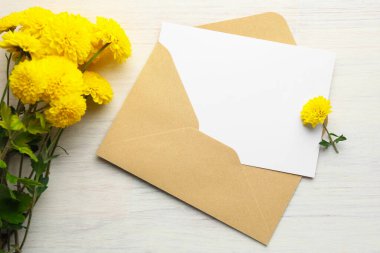 Zarfın içinde boş bir kart ve beyaz ahşap masanın üzerinde çiçekler, düz bir şekilde yatıyordu. Tasarım için model