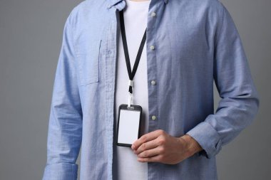 Gri arkaplanda boş rozet gösteren adam, yakın plan.