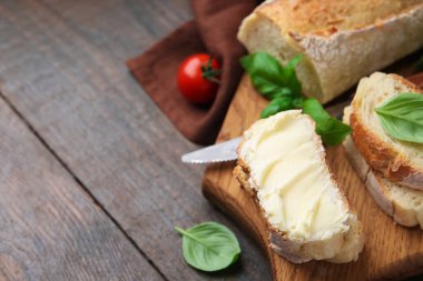 Tahta masada tereyağlı, fesleğenli, domatesli ve bıçaklı ekmek dilimleri, yakın plan. Metin için boşluk