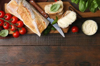 Tereyağlı, fesleğenli, domatesli ekmek dilimleri ve tahta masa üzerinde bıçak. Metin için boşluk