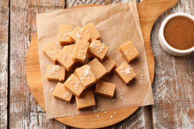 Tuzlu ve karamel soslu lezzetli şekerler ahşap masa üzerinde, düz yerde.