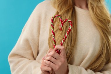 Açık mavi arka planda baston şekerli kadın, yakın plan.