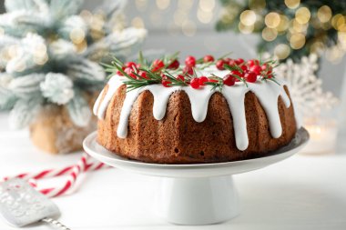 Beyaz ahşap masada kremalı, kızılcıklı ve biberiyeli lezzetli bir Noel pastası.