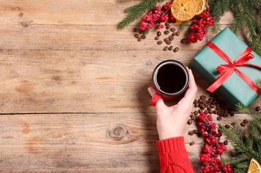 Aromatik kahve, hediye kutusu ve ahşap masada Noel dekoru olan bir kadın. Metin için boşluk
