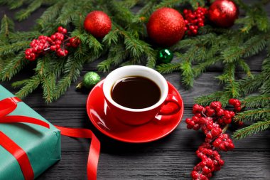 Fincanda romatik kahve, hediye kutusu ve siyah ahşap masada Noel dekoru, yakın plan.