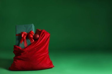 Noel hediyeli Noel Baba çantası ve yeşil arka planda takı. Metin için boşluk